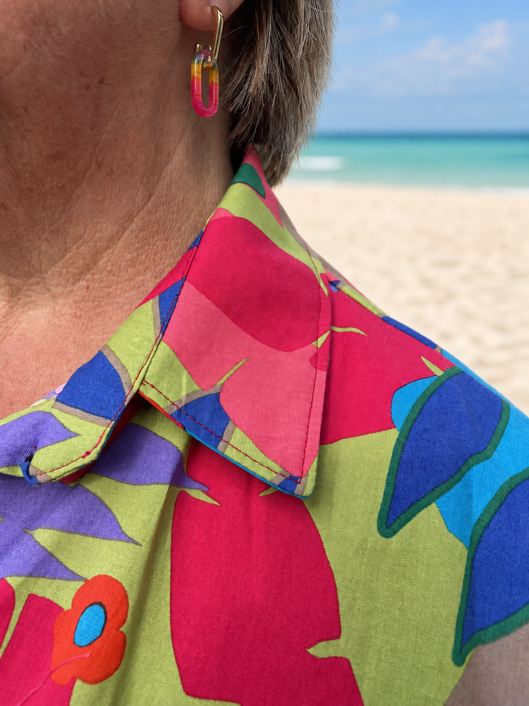Détail du chemisier sans manche Clo coloré sur une plage de sable fin