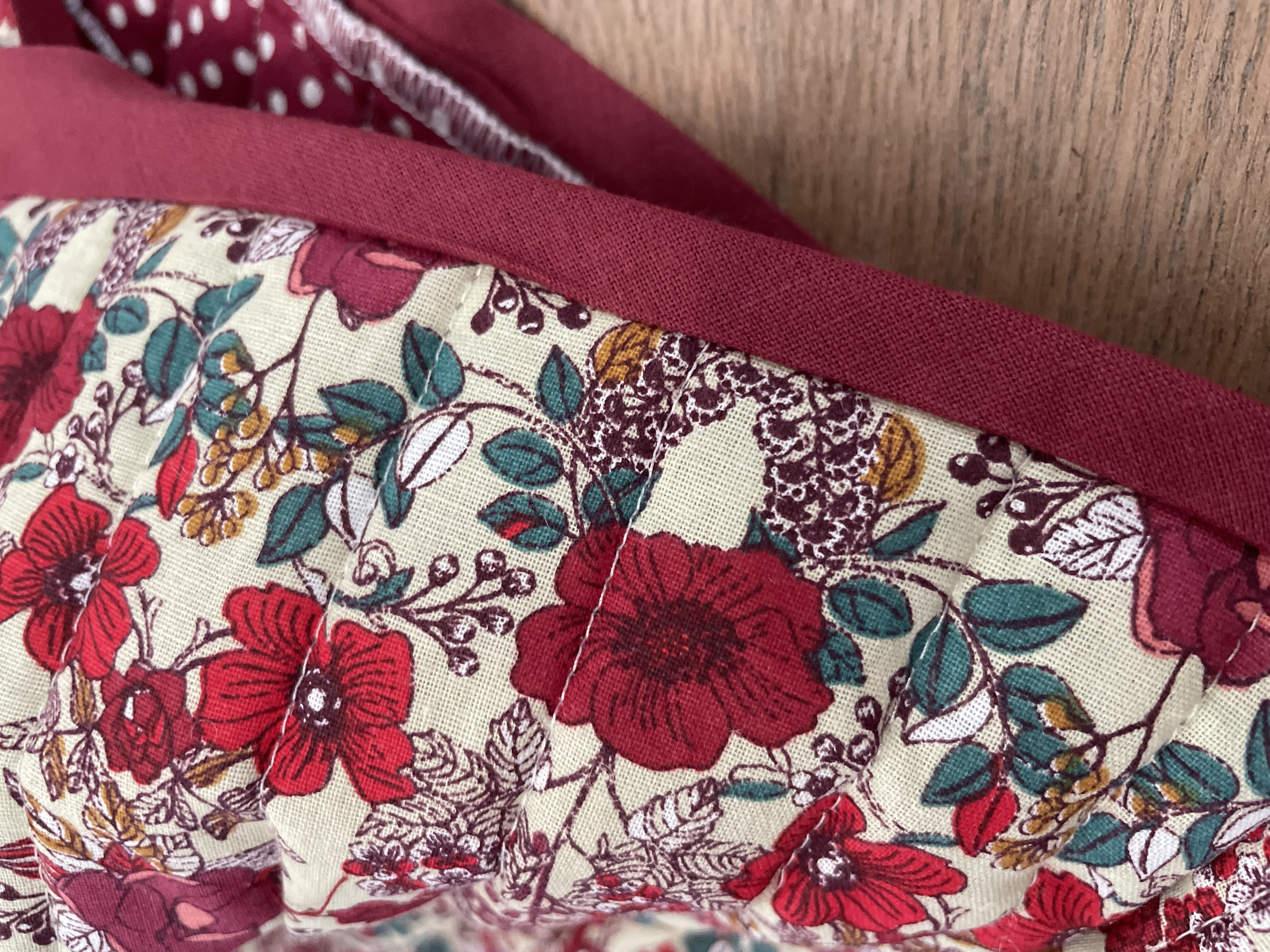 Détail du tissu fleuri, du biais bordeaux et de la doublure douce du gilet berger